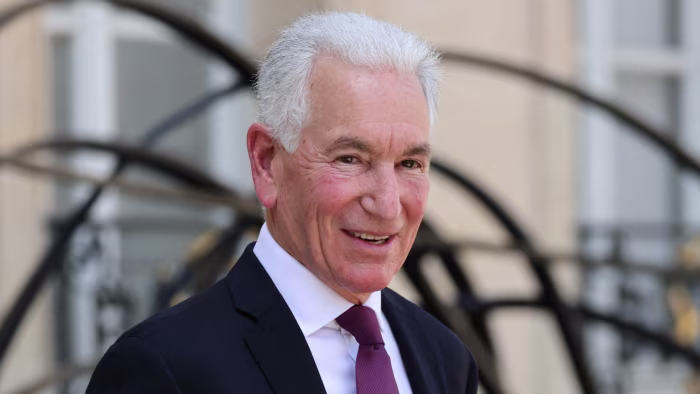 Charles Kushner smiles while wearing a dark suit and tie outside the Elysee Presidential Palace in Paris.