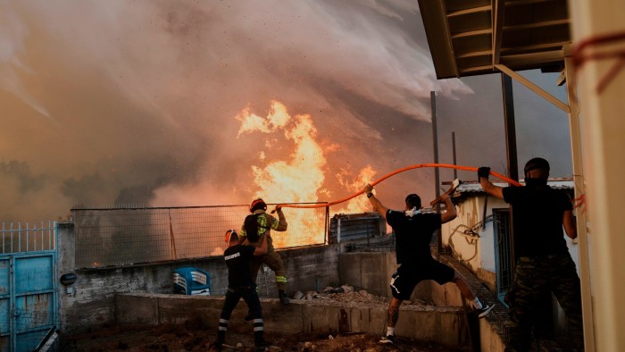 A firefighter and residents try to control the wildfire approaching a house in Patras city, western Greece on August 13, 2025