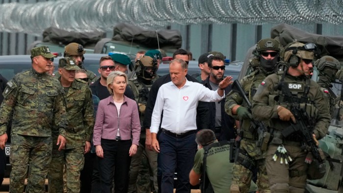 Donald Tusk and Ursula von der Leyen speak with Border Guard personnel near a barbed wire fence at the Polish-Belarus border.