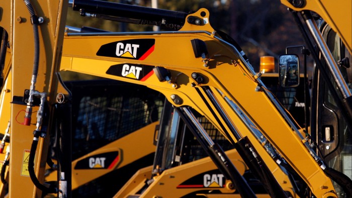 Several yellow CAT construction machines with visible hydraulic arms are lined up in a lot