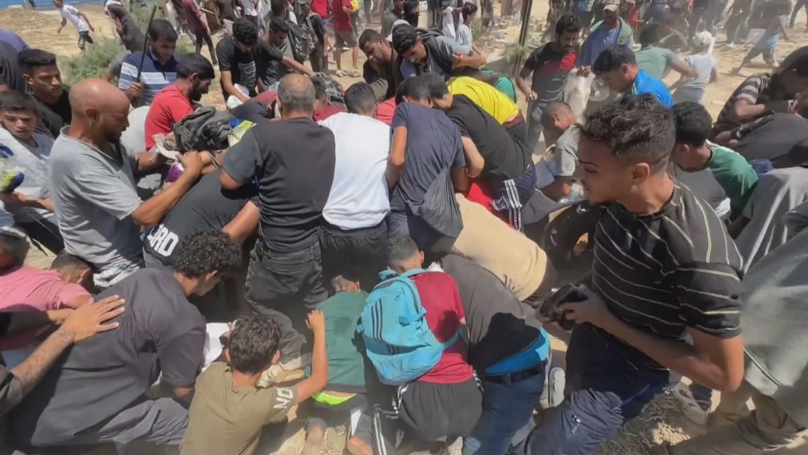 A group of Palestinians rush an aid drop site