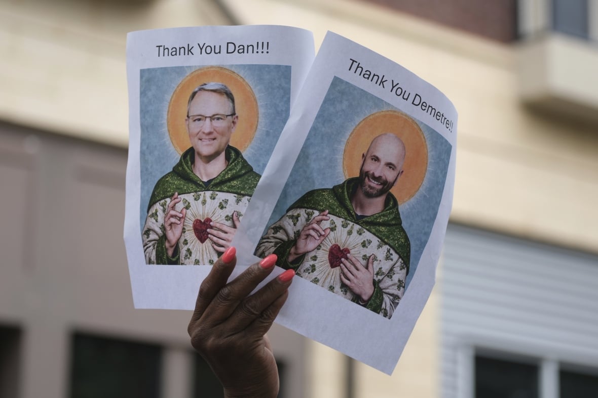 A person holds up images depicting the faces of two CDC scientific leaders who have resigned from the U.S. public health agency.