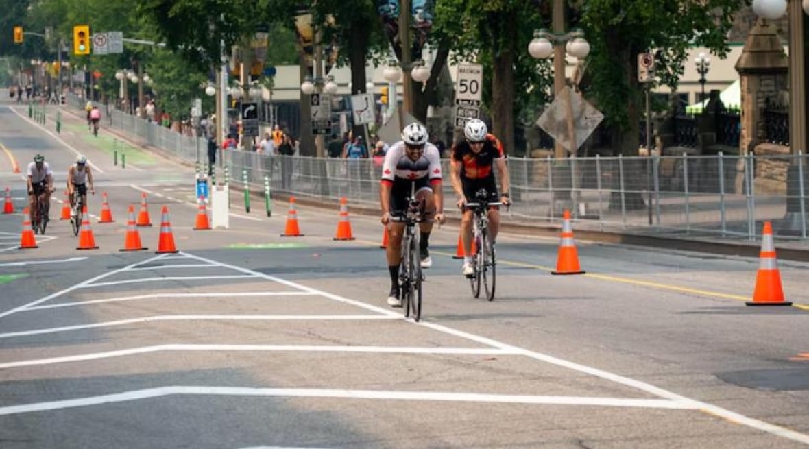 Several cyclists bike along a closed road in a city's downtown.