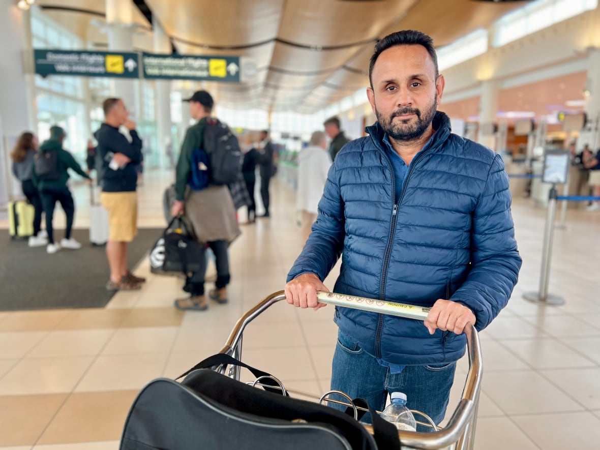 A man in a blue jacket pushing luggage. 
