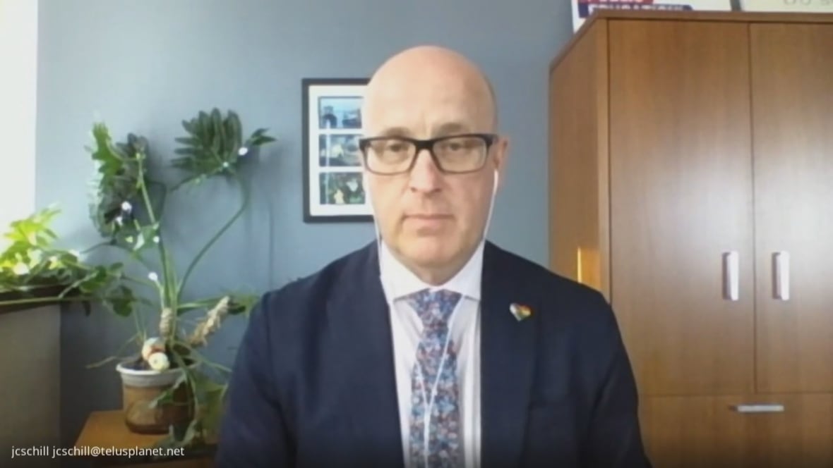 Jason Schilling, president of the Alberta Teachers’ Association, participates in an online interview. He wears a blue suit and wears white earbuds.