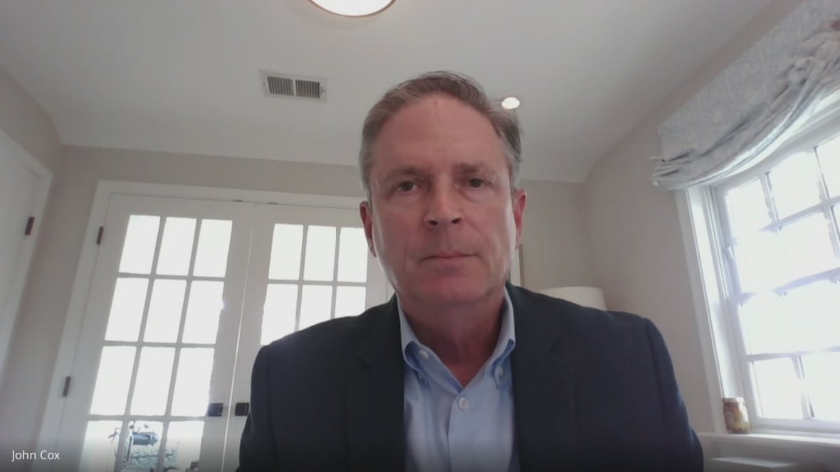 A man wearing a suit sits in a kitchen.