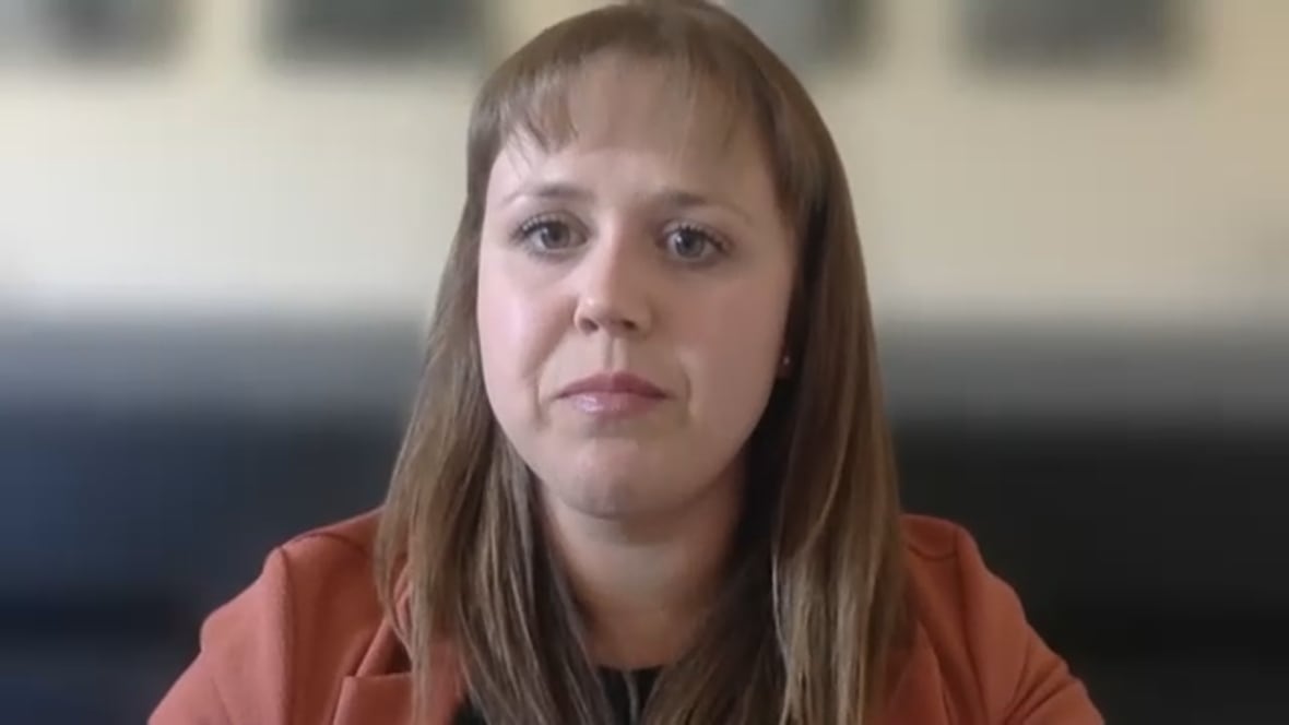 Woman with long, light brown hair in a dark orange blazer
