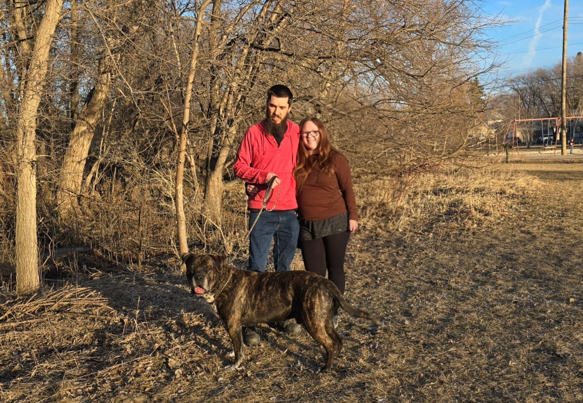 A man and a woman are at a forest with a dog.