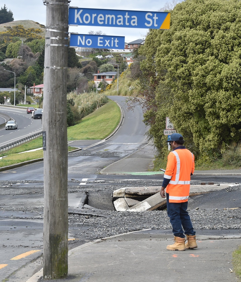 A worker inspects a sinkhole thought to be caused by a burst water main in Green Island on...