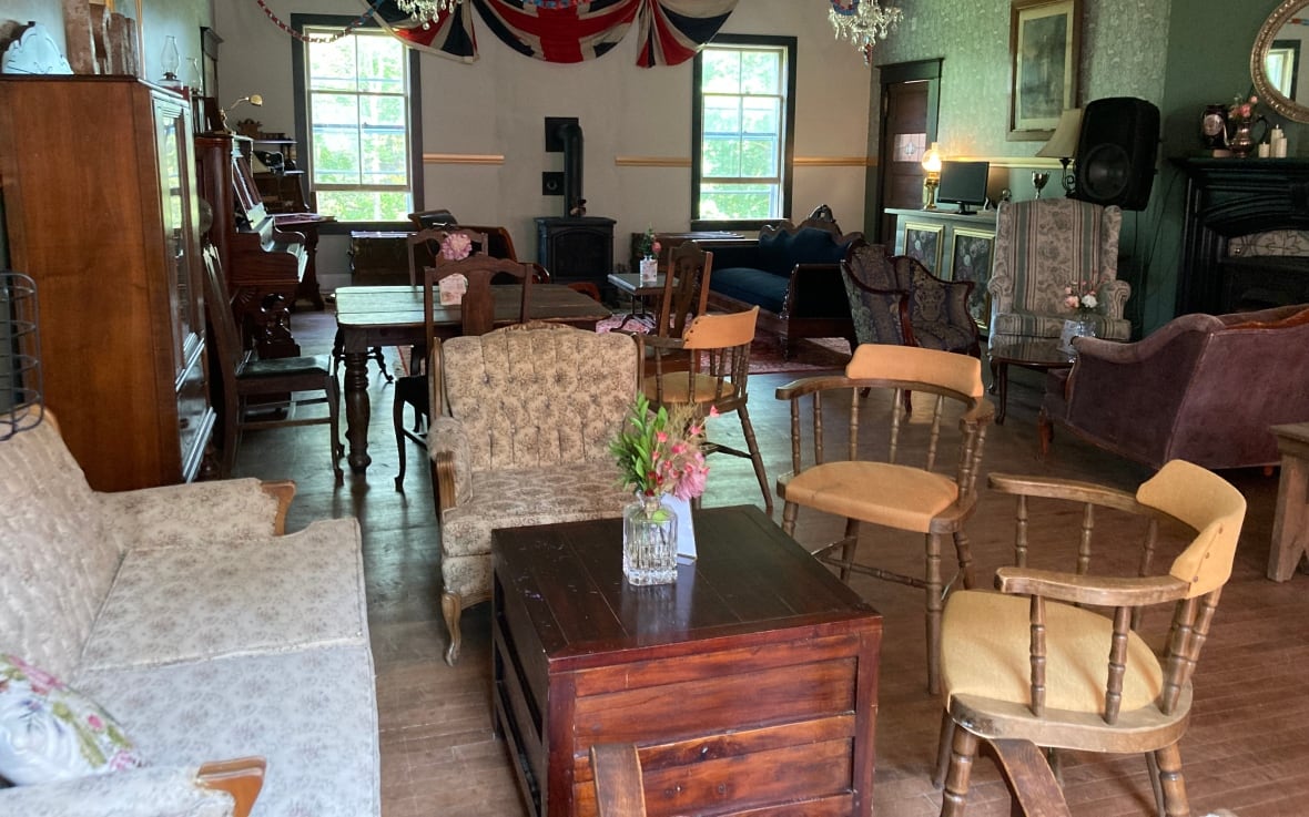 A room with mismatched chairs placed around tables and chests