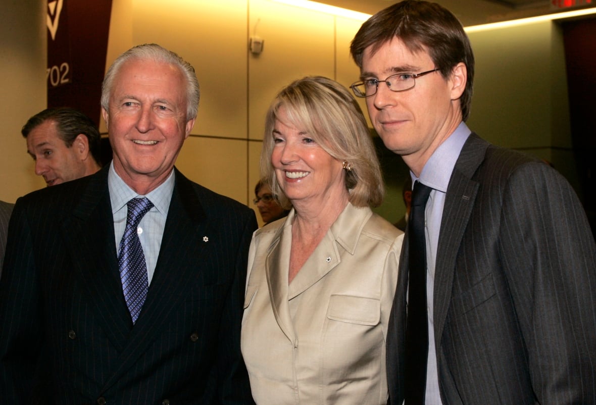 Three people pose for photographs.