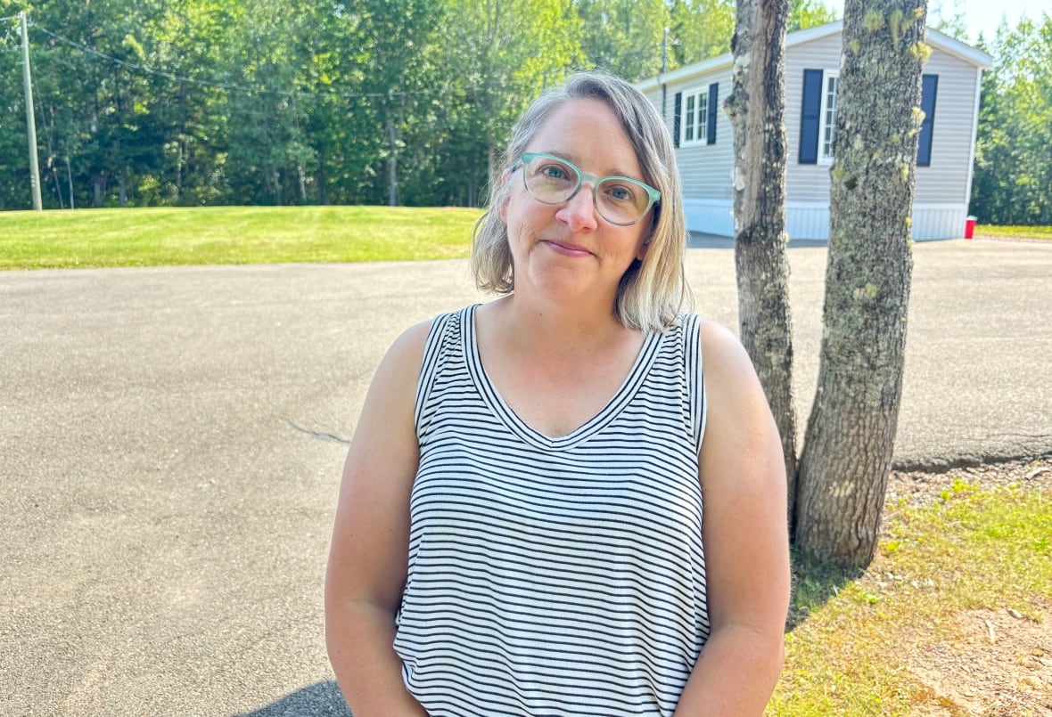 A woman standing in front of a mini home.
