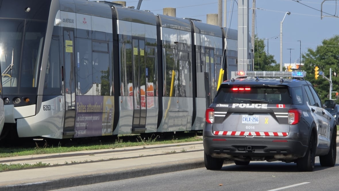 A Toronto police car parked next to a light rail transit train