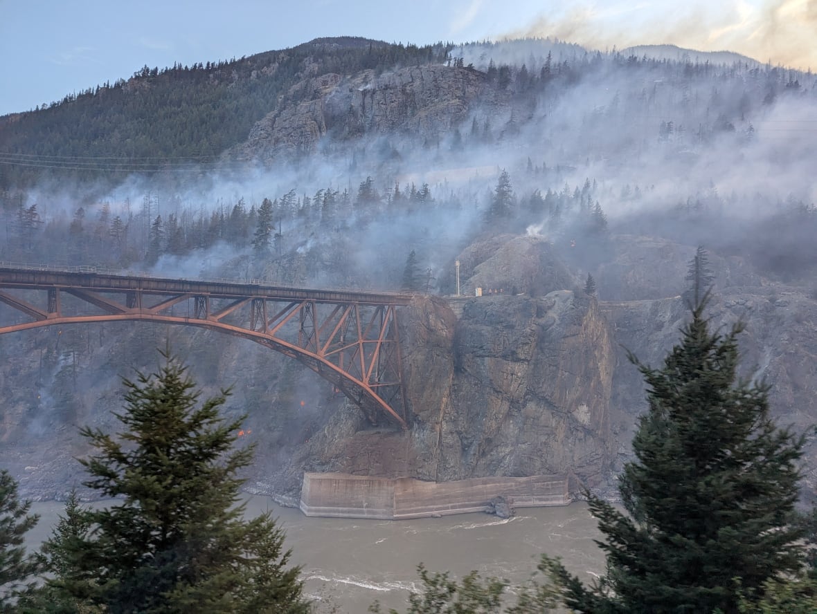 A bridge over a river in the mountains surrounded by smoke.