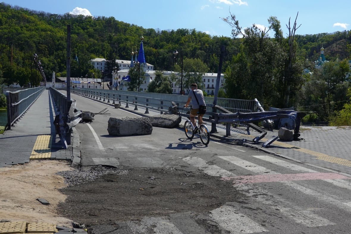 A man rides a bicycle along a damaged bridge in Ukraine's Donetsk region.