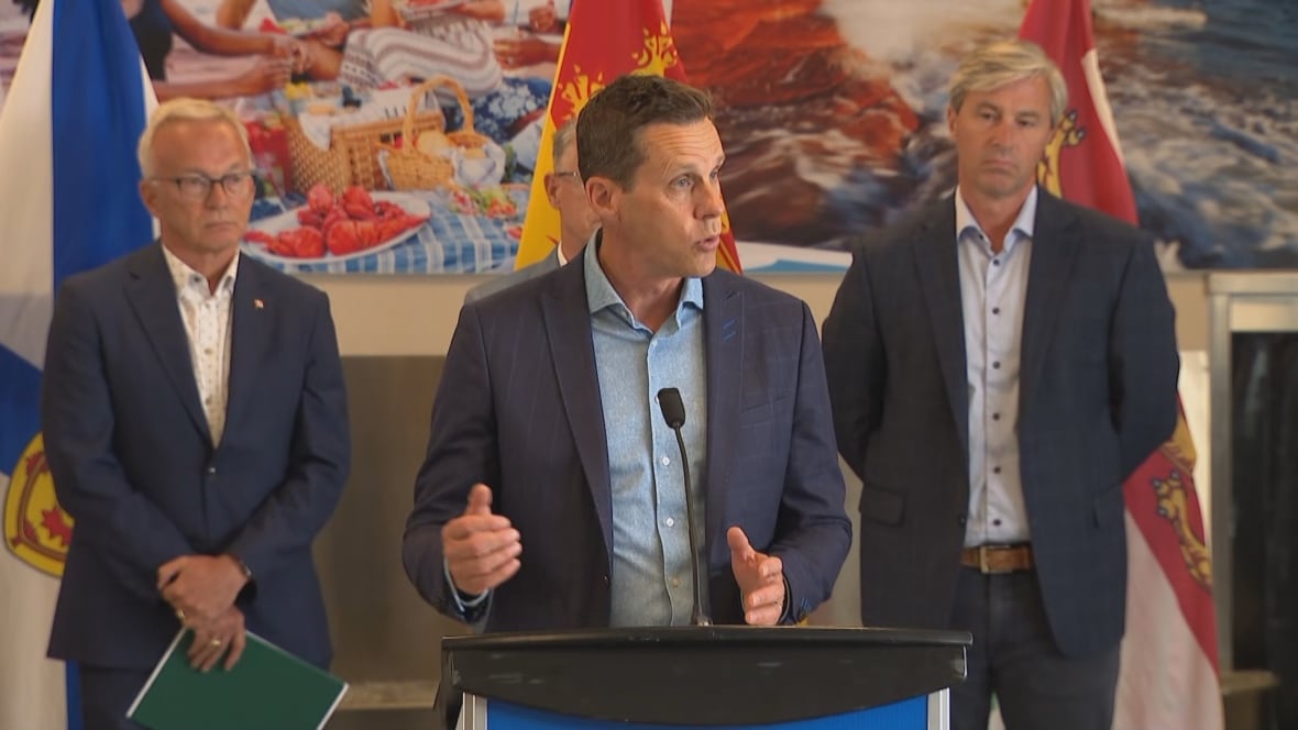 A man stands at a podium with three other men behind him. 