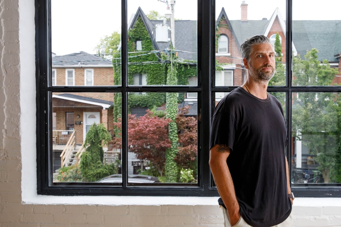 A man stands next to a large window.