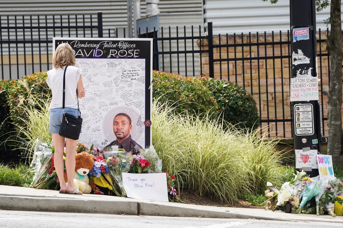 A woman standing by a makeshift memorial for David Rose, a police officer killed while stopping a gunman at the Atlanta headquarters of the U.S. CDC.