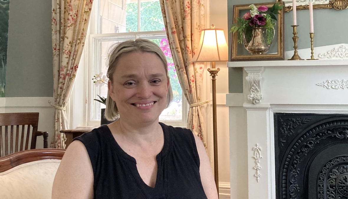 A woman with short blond hair sitting in a vintage parlour room