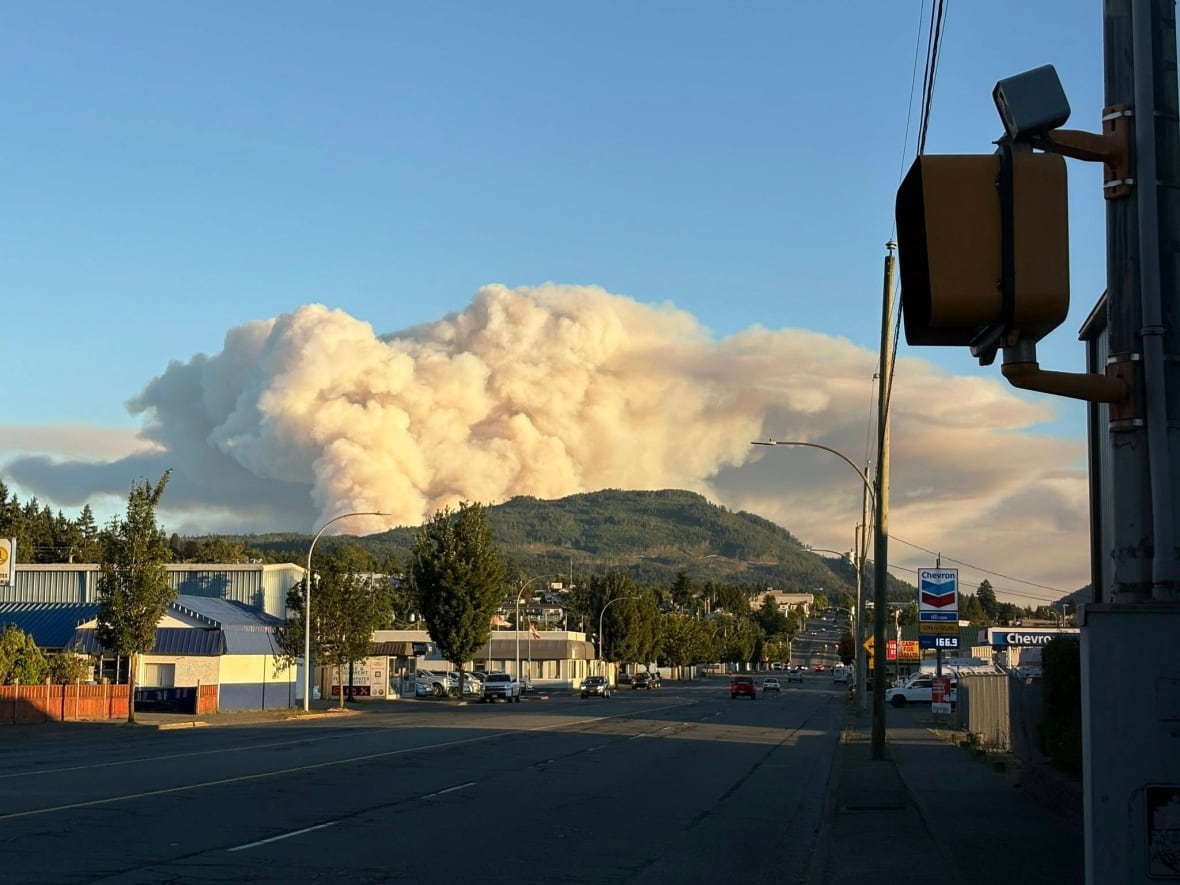 Smoke arises from a hill behind a city street.