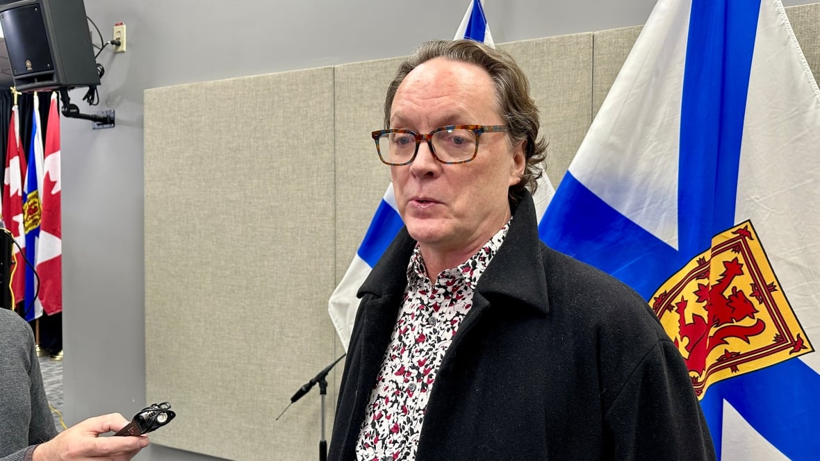 man stands near Nova Scotia flags.