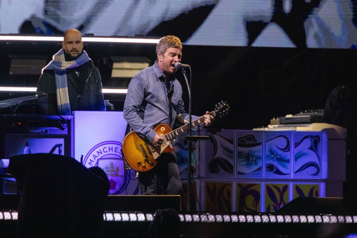 A man playing guitar sings into a microphone.