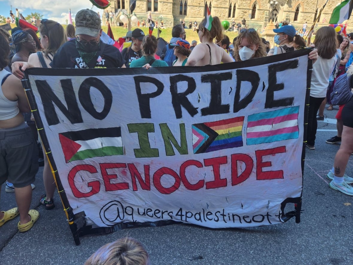 A protest sign is held up in front of a crowd of people.