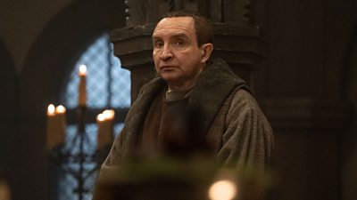 King Edward (Eddie Marsan) is central in the image staring off into the distance in a castle with candles burning behind him