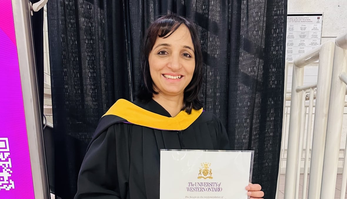 Ravinder Kaur Sidhu wearing graduation robe and holding a diploma. 