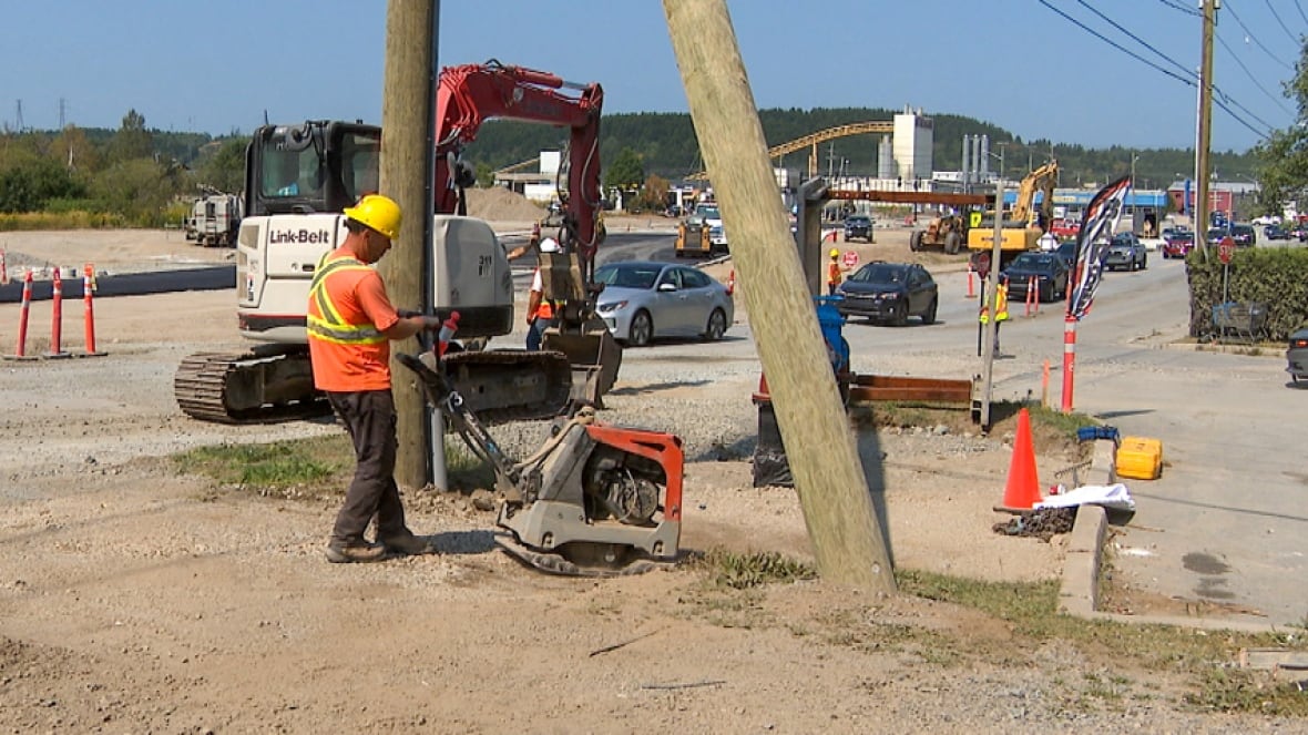 A road crew worker operates a machine that compacts the ground before the asphalt is laid.