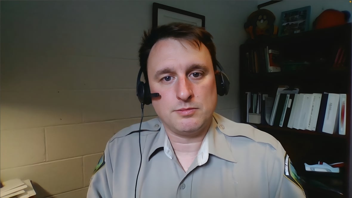 A man wearing a uniform and a headset is shown in his office.