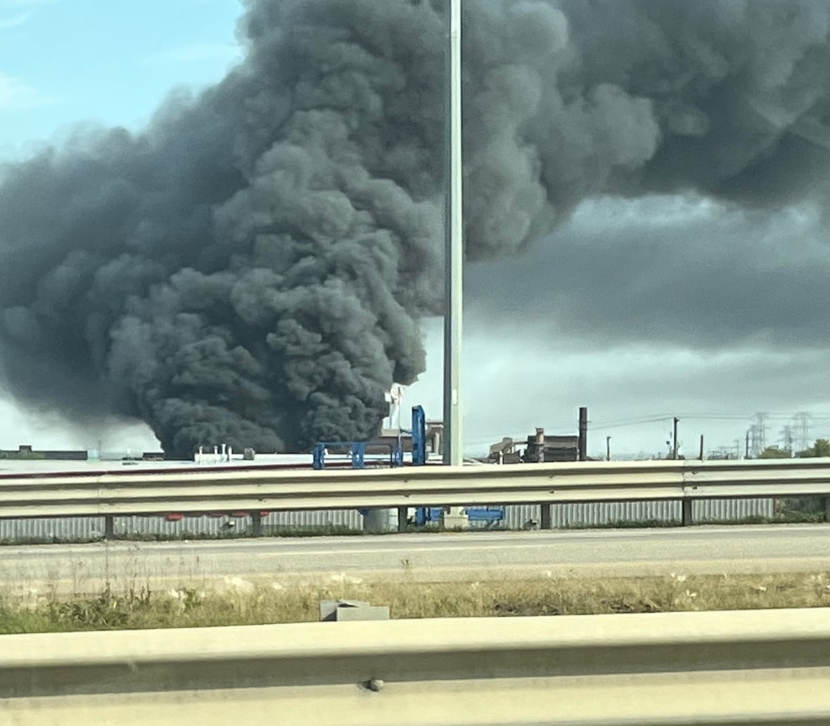 A large plume of black smoke with a guardrail. 
