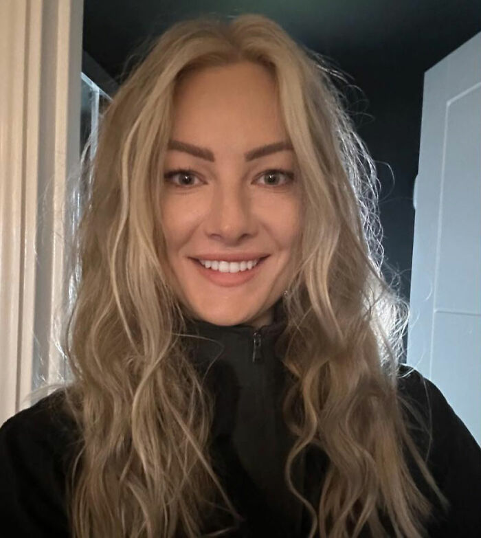 Woman with long blonde hair smiling indoors, connected to story about 15,500-ft jump after breakup choice.