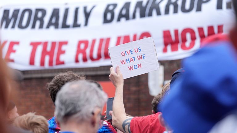 A Crystal Palace fan holding a sign during a protest march. Pic: PA
