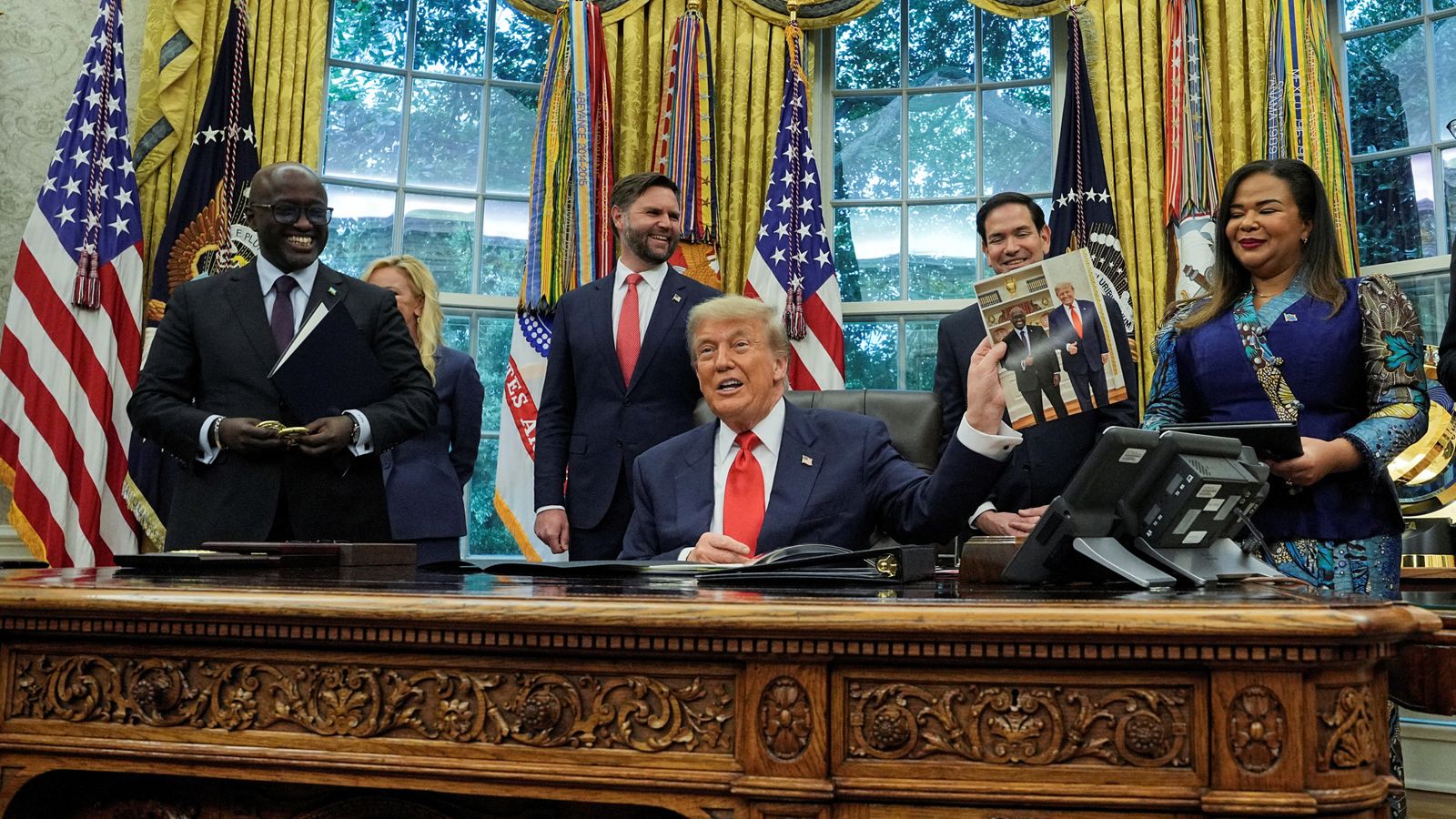 Donald Trump holds a picture of himself with Rwanda's foreign minister Olivier Nduhungirehe, at a meeting in June. Pic: Reuters