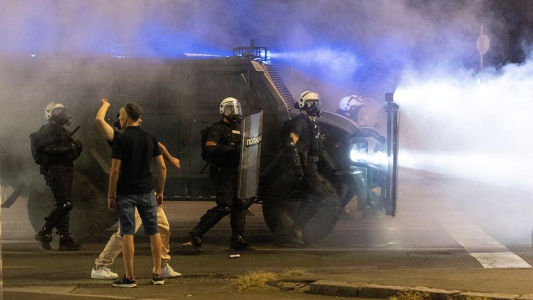 Protesters react next to police officers deployed during anti-government demonstrations in Belgrade, Serbia. Pic: Reuters