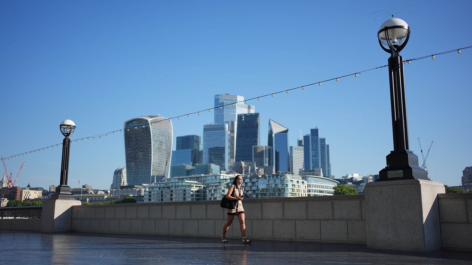 A person walks along The Queen's Walk near Tower Bridge in London