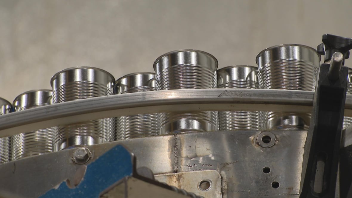 Cans sit along a factory production line.