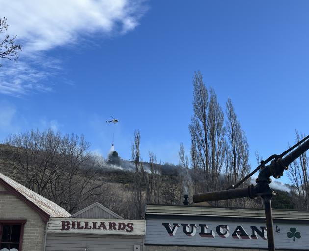 A helicopter with a monsoon bucket attacks the blaze behind the iconic Vulcan Hotel in St Bathans...