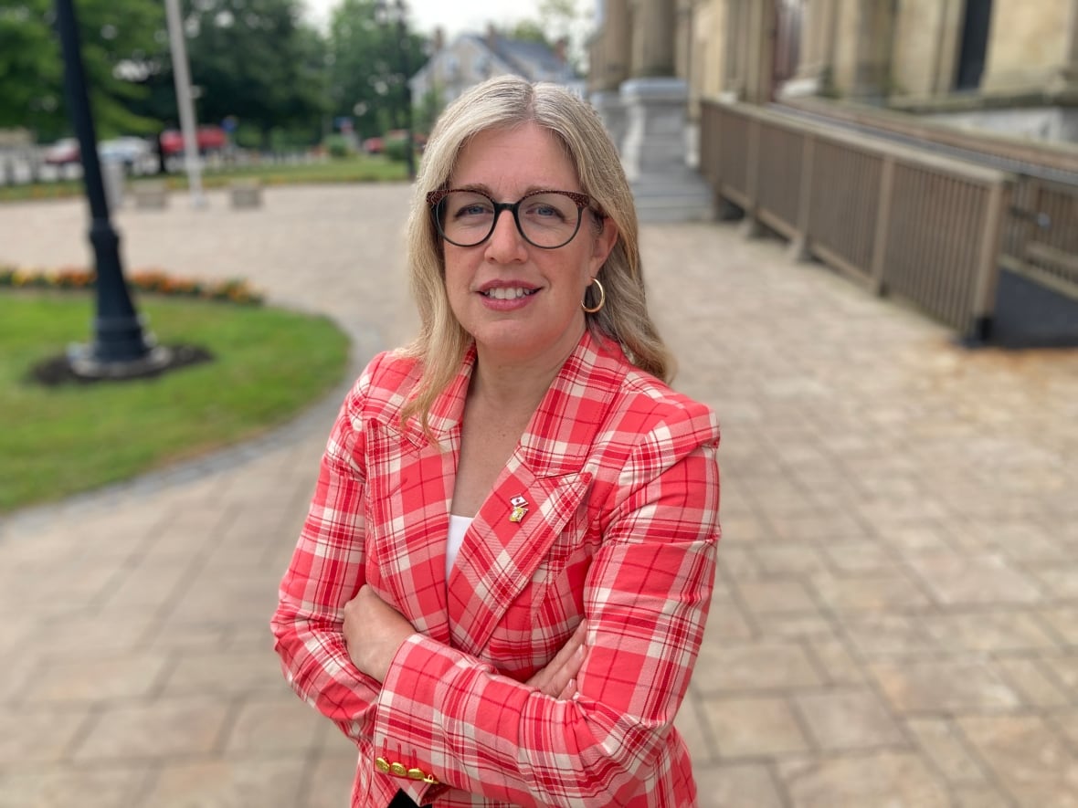 A woman smiles while wearing a red blazer