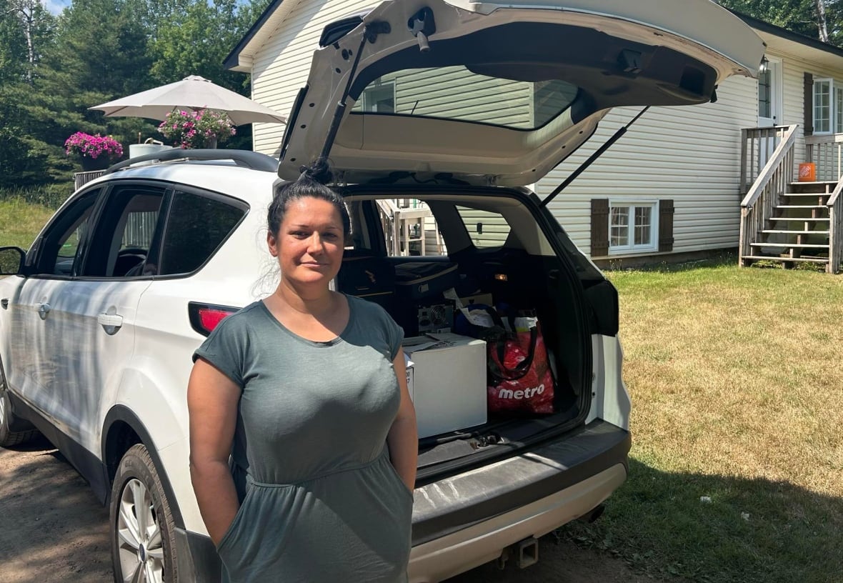 A woman in front of a packed SUV and a white house.