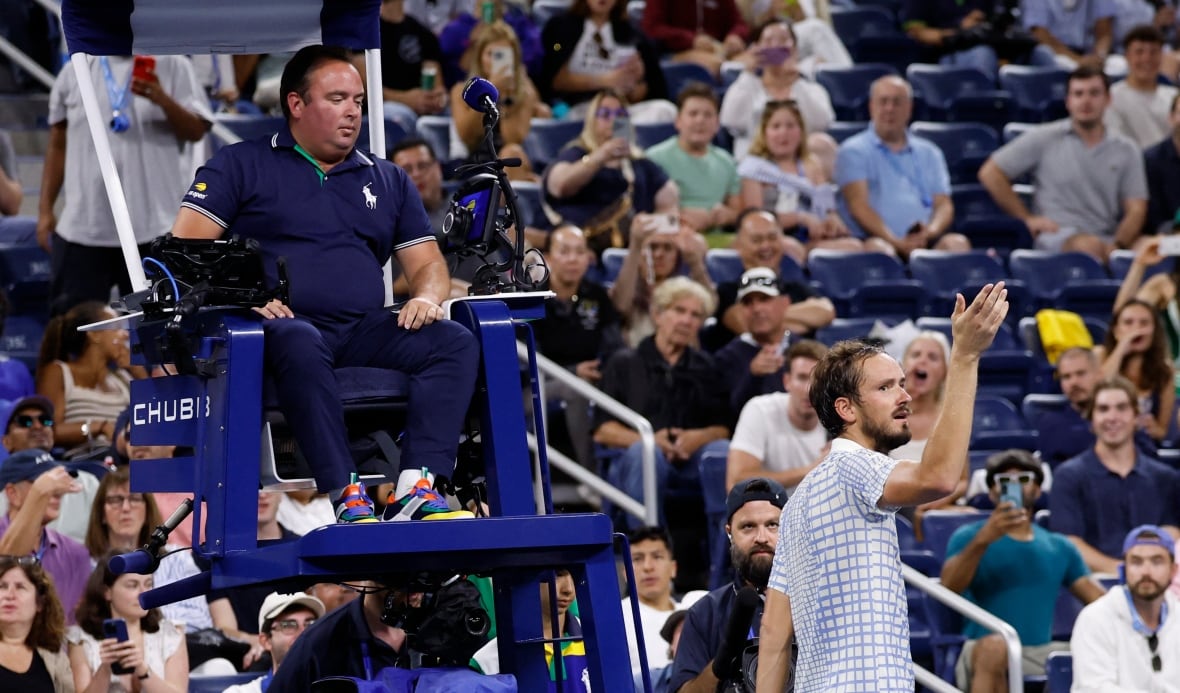 A man speaks to a referee in front of a crowd