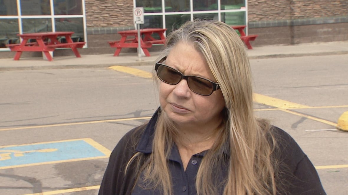 A woman stands in a parking lot.