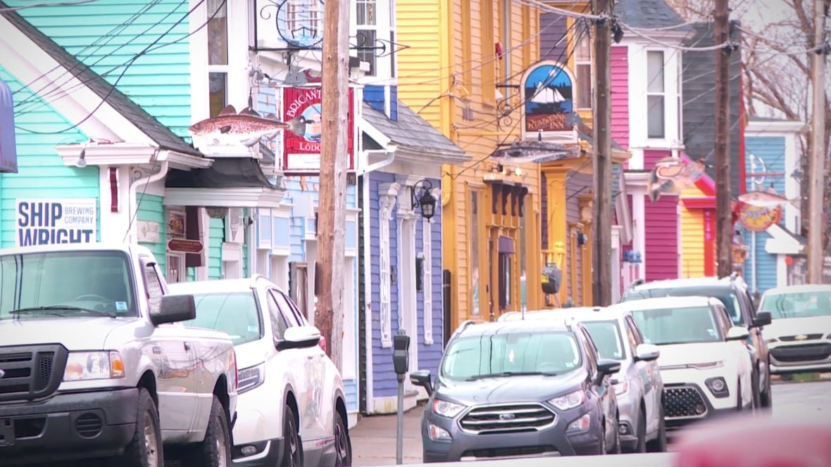 Cars are parked on a busy street with colourful buildings behind them.