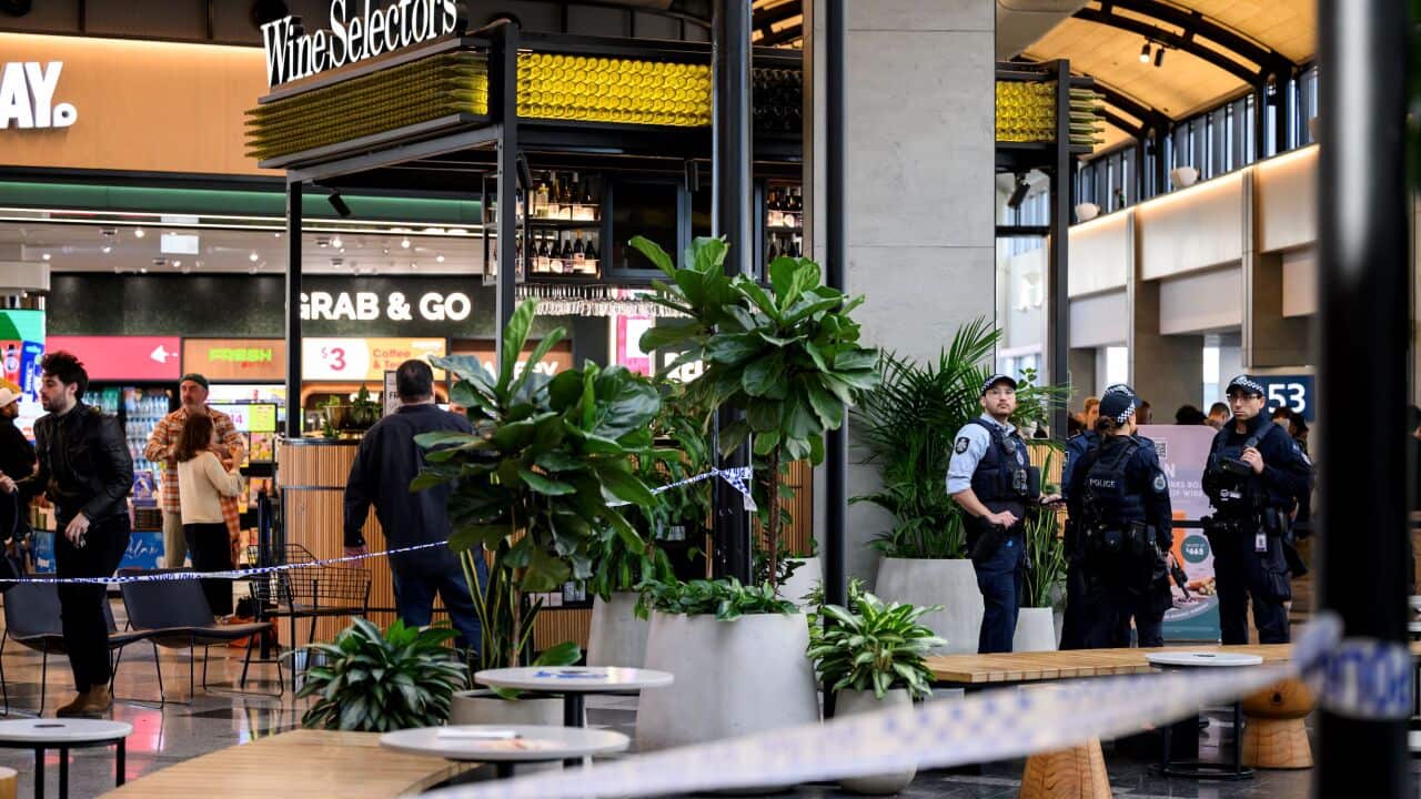 Police and other people standing at an airport terminal. Police tape covers a portion of it.