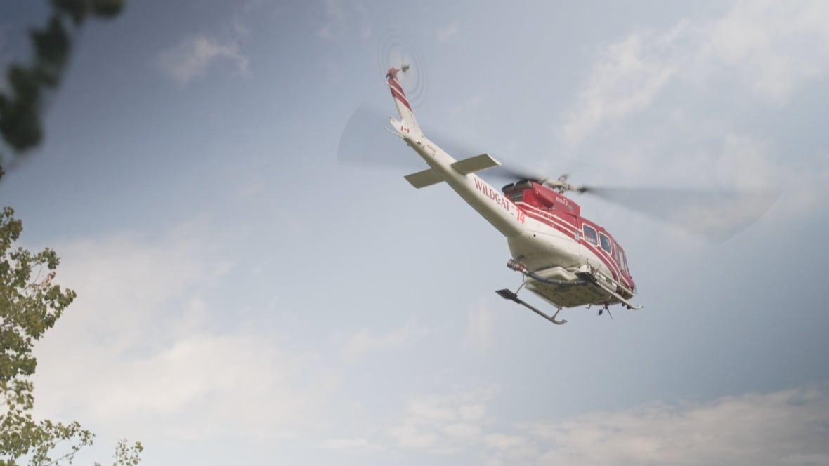 A red and white helicopter, seen from below, flying