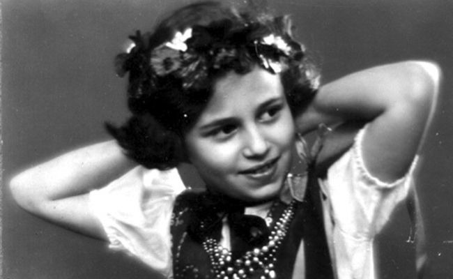 Young Ruth Posner wearing a floral wreath and traditional attire.