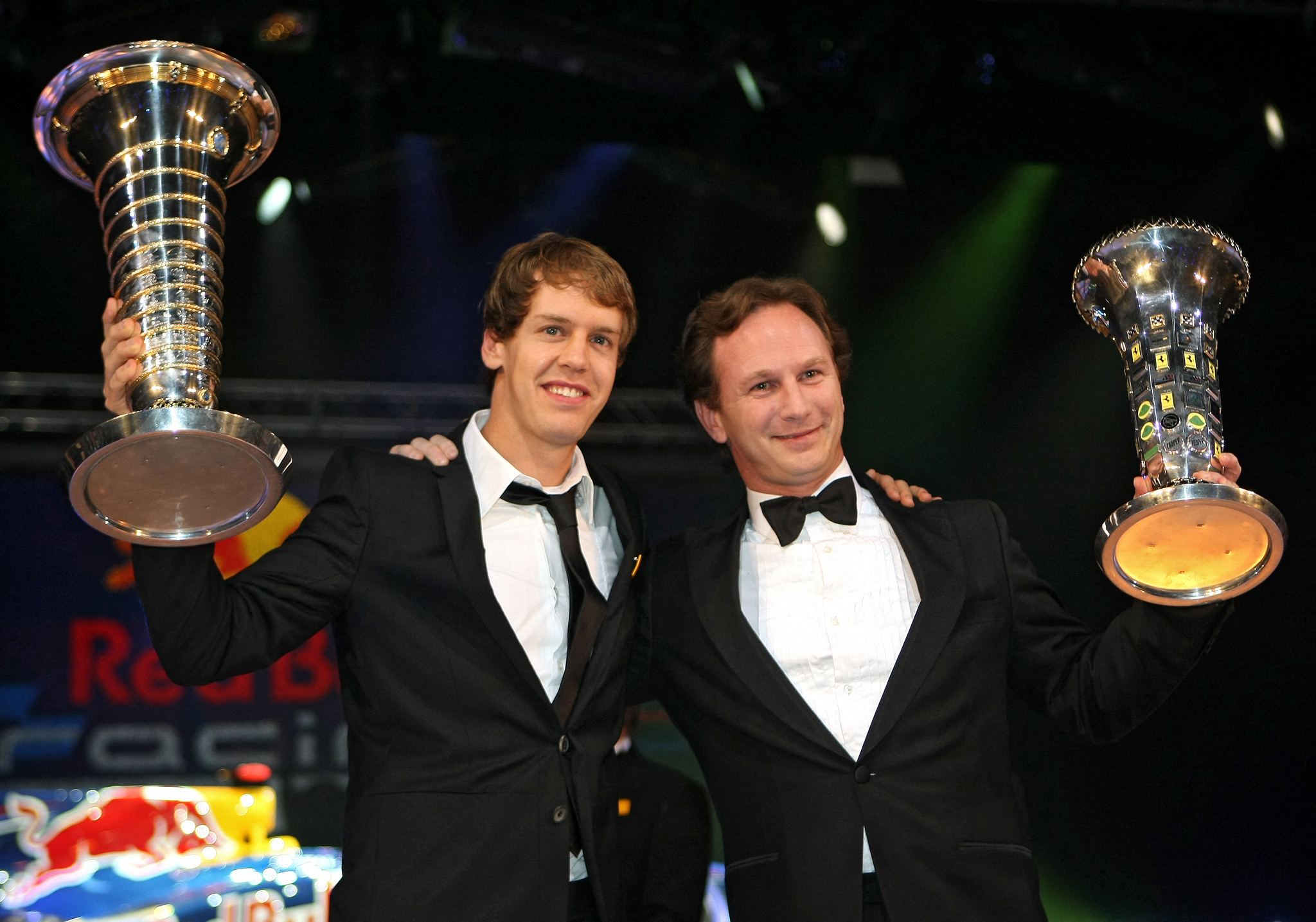 Sebastien Vettel and Christian Horner holding trophies at an awards ceremony.