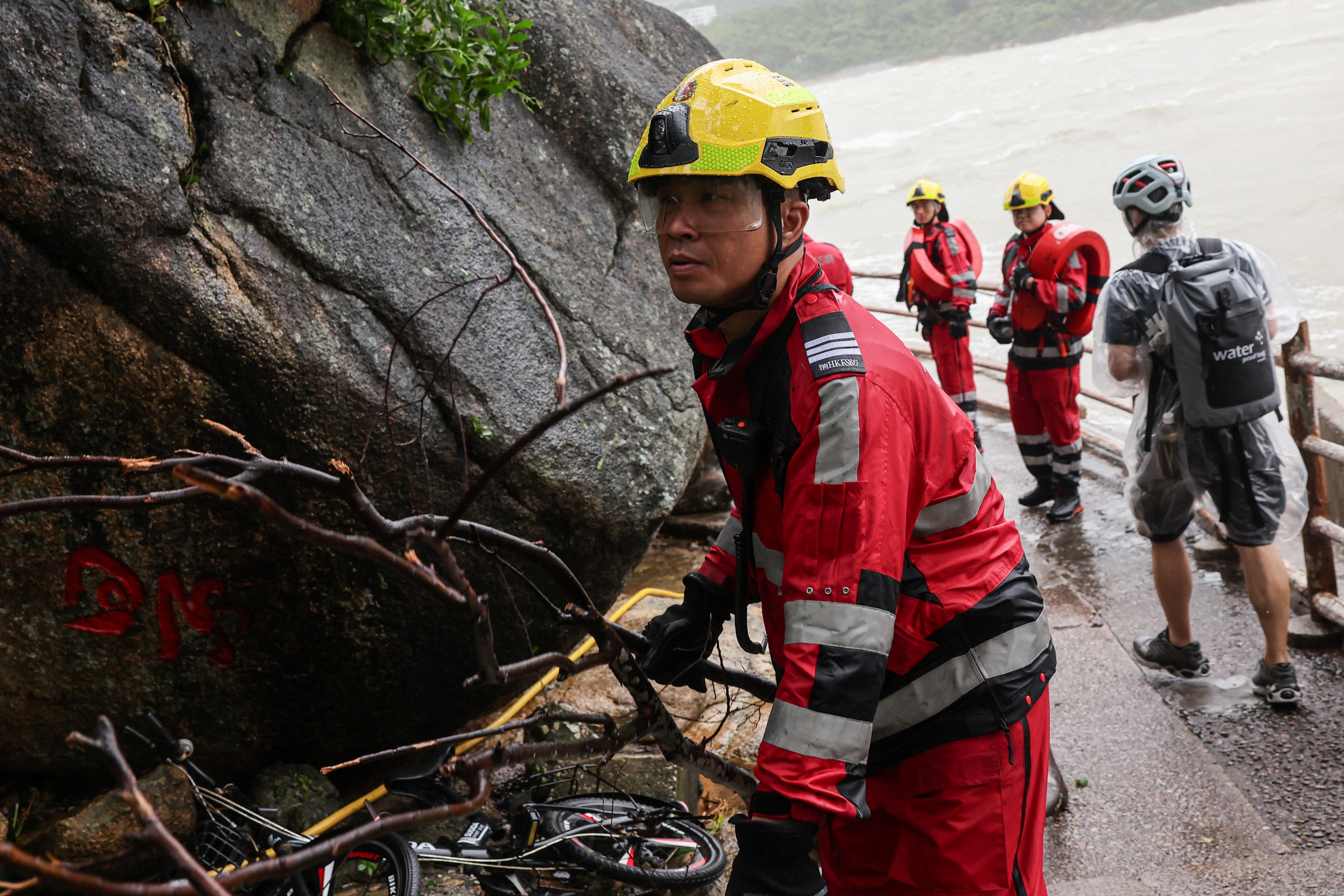 A firefighter in Hong Kong moves a fallen branch as he assesses damage after Super Typhoon Ragasa.