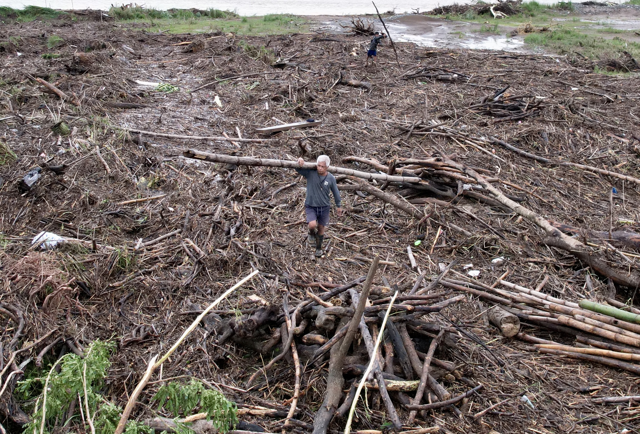 An aerial drone photo shows a villager collecting washed-up logs and debris in the typhoon-hit town of Vintar, Ilocos Norte province, Philippines.